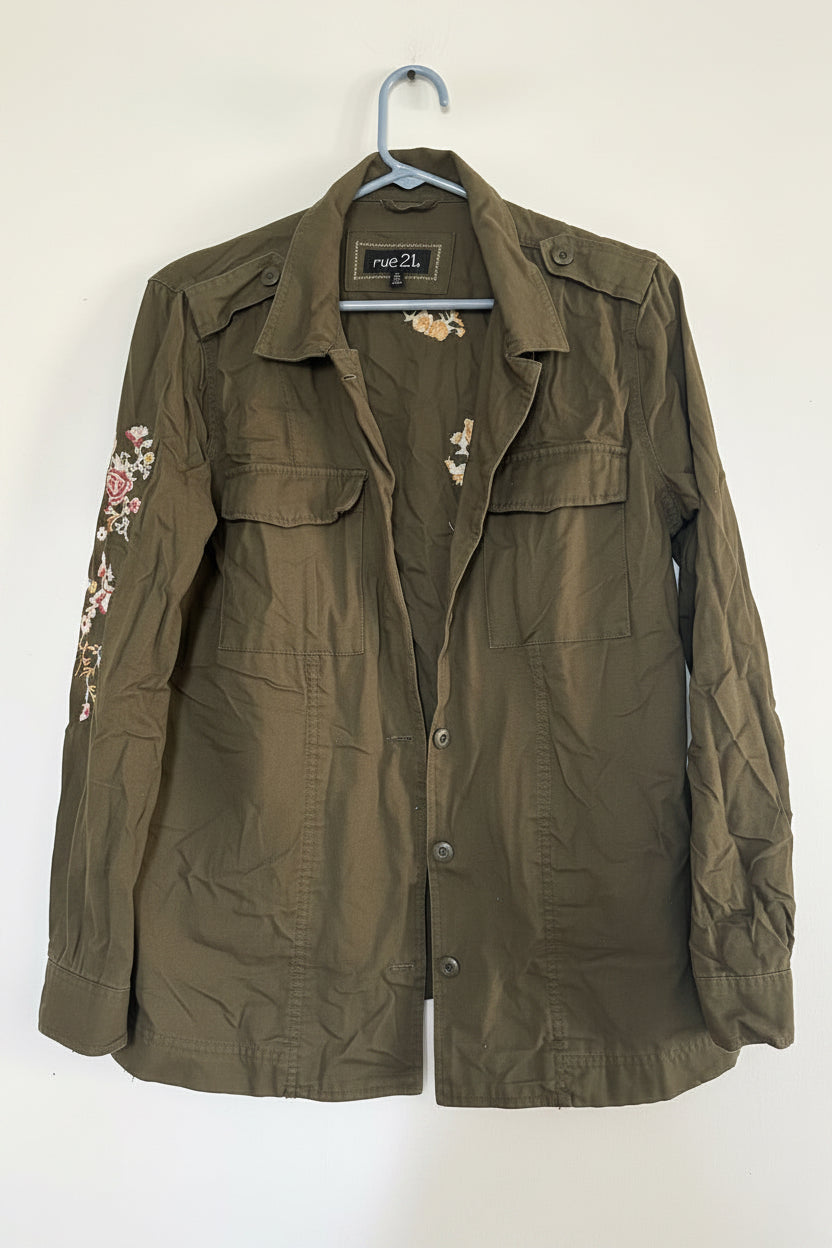 Folded olive green jacket with floral embroidery on a white background